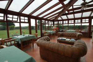 un giardino d'inverno con tavoli e divani in un ristorante di Pointers Guest House a Wistow