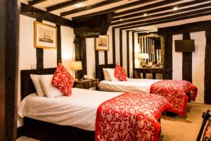 a hotel room with two beds with red pillows at Mermaid Inn in Rye