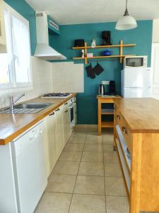 a kitchen with white cabinets and a blue wall at Clos Margottières in Le Val-Saint-Père