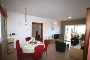 Apartment Andrina في فانتاسيسي: غرفة طعام مع طاولة وكراسي حمراء