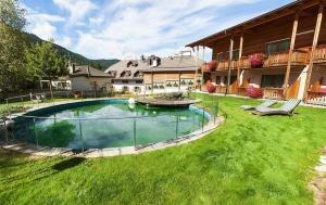 a large yard with a swimming pool in front of a house at Hotel Gratschwirt in Dobbiaco