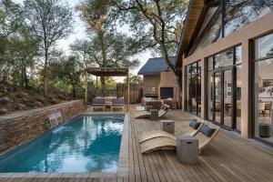 a swimming pool with chairs and a house at Kruger Gate Hotel in Skukuza
