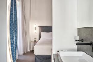 
a hotel room with a white bed and white walls at NLH MONASTIRAKI - Neighborhood Lifestyle Hotels in Athens

