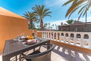 d'une table et de chaises sur un balcon avec des palmiers. dans l'établissement Complejo Tenerife Royal Garden, à Playa de las Americas