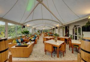 un restaurante con mesas, sillas y ventanas en Khanvel Resort, en Silvassa