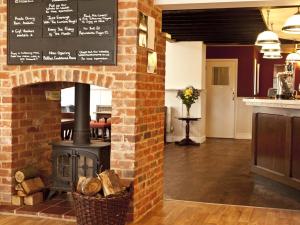 a brick fireplace with a stove in a restaurant at Marsham Arms Inn in Hevingham