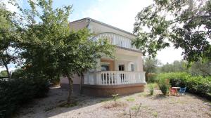 a house with a white balcony and a yard at Apartment Ljudmila in Sveti Anton