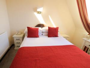 a bedroom with a red and white bed with red pillows at Pilgrims Hotel in Canterbury