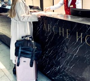 une femme avec une valise debout à côté d'un comptoir dans l'établissement Arche Hotel Krakowska, à Varsovie