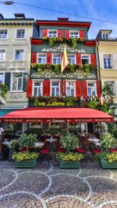 a building with a restaurant with red umbrellas and plants at Hotel Alte Laterne in Baden-Baden