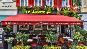 a restaurant with tables and chairs and a red awning at Hotel Laterne in Baden-Baden