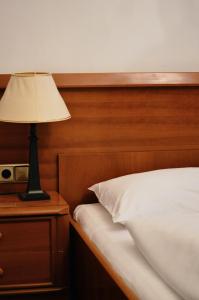 a lamp on a nightstand next to a bed at Hotel Pension Lumes - Self Check In in Vienna