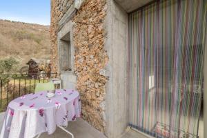 a table with a pink table cloth on a balcony at Maison confortable proche du parc national du Mercantour. in La Bollène-Vésubie
