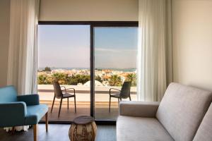 een woonkamer met een bank en stoelen en een groot raam bij Agua Hotels Alvor Jardim in Alvor