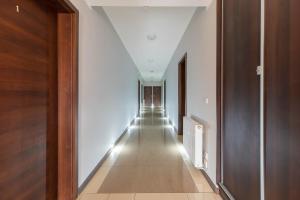 a hallway with white walls and a long hallway with lights at Awenturyn - Pokoje Apartamenty Noclegi Grzybowo in Grzybowo