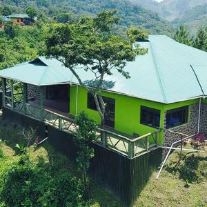 ein grünes Haus mit grünem Dach auf einem Hügel in der Unterkunft Gorilla Hills Eco-lodge in Kisoro