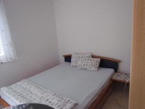 a small bedroom with a bed with white sheets and pillows at Holiday house Damir in Sveti Filip i Jakov