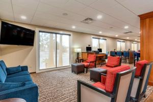 uma sala de espera com cadeiras e mesas e uma televisão em Comfort Suites Niceville Near Eglin Air Force Base em Niceville
