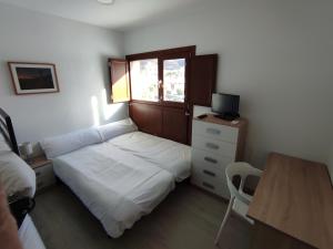 een kleine slaapkamer met een bed en een bureau met een computer bij Mirador de Sabayés in Sabayés