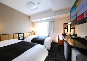a hotel room with two beds and a flat screen tv at APA Hotel Asakusa Tawaramachi Ekimae in Tokyo