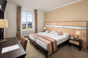 Cette chambre comprend un lit, un bureau et une fenêtre. dans l'établissement Hôtel des Alpes, à Nyon