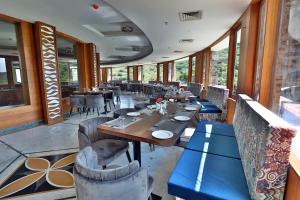 a restaurant with wooden tables and chairs and windows at Seasons Park Resort in Udaipur
