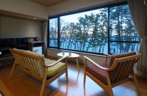 Habitación con mesa, 2 sillas y ventana grande. en Hamabeno Ryouriyado Houraikan, en Kamaishi