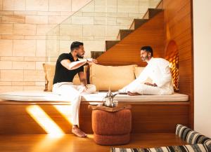 two men sitting on a bed in a room at SHIRVAN Hotel City Yard Jeddah in Jeddah