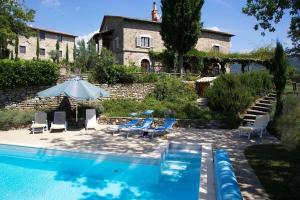 - une piscine en face d'une maison avec des chaises et un parasol dans l'établissement Villa Calcina, Beautiful Tuscan Farmhouse, à Pieve Santo Stefano