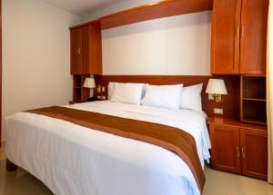 1 dormitorio con 1 cama blanca grande y armarios de madera en Retama Hotel, en Tacna