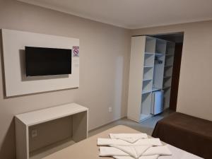 sala de estar con TV y mesa con toallas en Hotel Jardim do Mar, en Torres