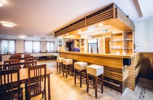 a restaurant with a bar with wooden tables and chairs at Natur Hotel Kövestető in Hosszúhétény-Szőlőhegy