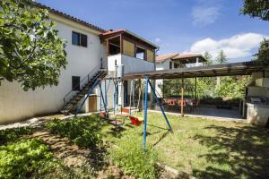 a swing set in a yard in front of a house at Apartment Vili in Pinezici