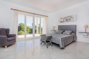 a white bedroom with a bed and a chair at Villa Quiros 2 in El Port +29 photos