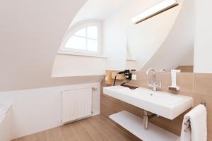 ein weißes Bad mit einem Waschbecken und einem Fenster in der Unterkunft Villa Gelbmann - Ferienwohnungen Velden in Velden am Wörthersee