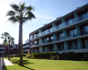a palm tree in front of a building at Agua Hotels Riverside in Ferragudo
