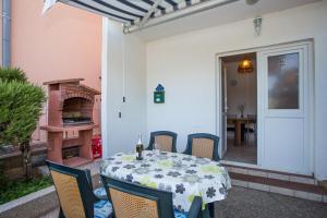 a table and chairs on a patio with a table and a fireplace at Apartments Mala Karla 1685 in Seget Vranjica