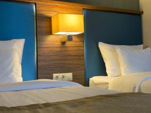 Barack Thermal Hotel and Spa في تيسزاكيتسيكيه: غرفة فندقية بسريرين واضاءة على الحائط