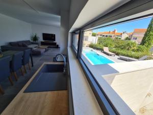 a living room with a large window and a swimming pool at SPA Apartment Vito in Vodice