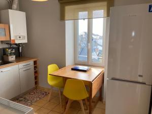 a kitchen with a wooden table and yellow chairs at L'escale Granvillaise in Granville