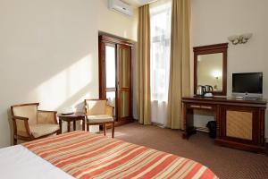 Habitación de hotel con cama, escritorio y TV. en Atrium Hotel Ateneu City Center, en Bucarest