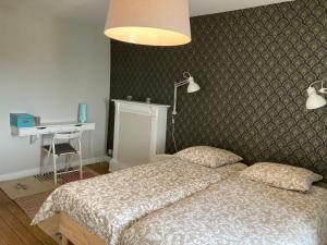 a bedroom with a bed and a desk and a lamp at L'escale Granvillaise in Granville