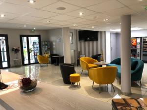 a lobby with yellow chairs and tables in a store at Contact Hôtel Lunotel Saint Lô in Saint Lo