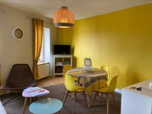 une salle à manger avec des murs jaunes, une table et des chaises dans l'établissement L'escale Granvillaise, à Granville