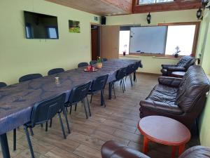 une salle de conférence avec une grande table, des chaises et un écran dans l'établissement Metsjärve puhkemaja, à Puskaru