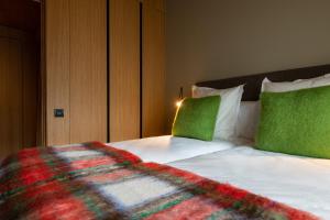 Una cama con almohadas verdes y una manta. en Vip Residences Andorra, en El Tarter