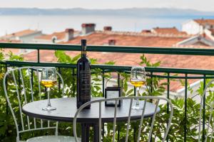 a table with two glasses of wine on a balcony at Apartments Leut 80m from the Sea in Podgora +17 photos