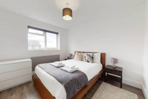 1 dormitorio blanco con 1 cama con 2 toallas en Amazing 3 Bedroom Flat - 4mins to tube station, en Londres