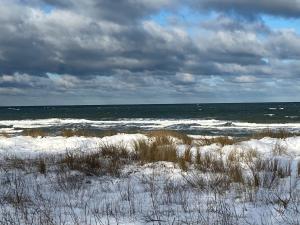 einen schneebedeckten Strand mit dem Ozean im Hintergrund in der Unterkunft Gästehaus Schmidt in Boltenhagen