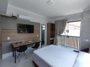 a bedroom with a bed and a desk and a tv at Residencial Batista in Bombinhas